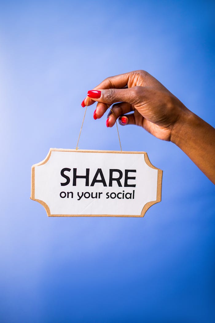 Close-up of a hand holding a Share on your social sign on a vibrant blue backdrop.
